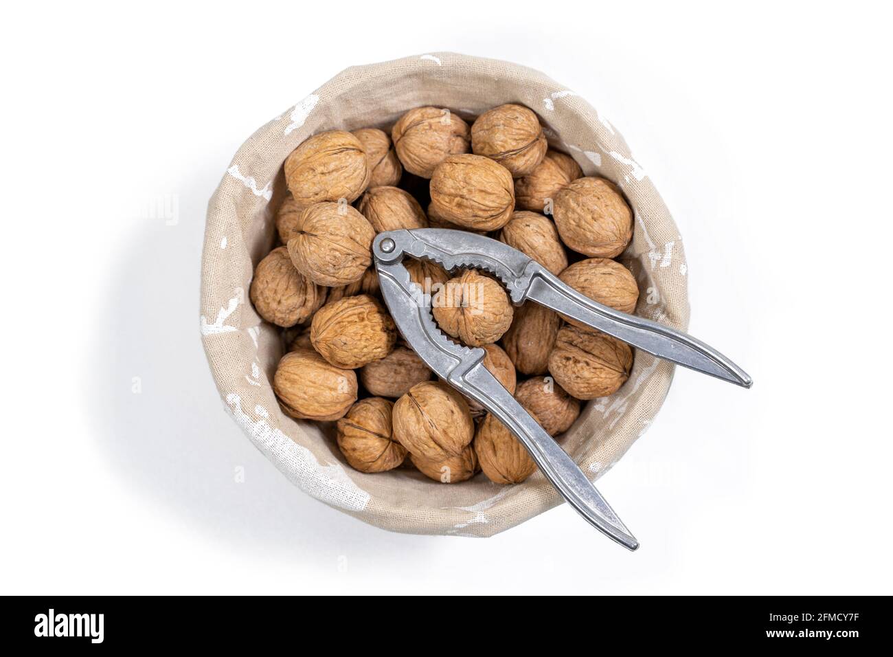 basket with whole walnuts and nutcracker, top view. isolate on white background Stock Photo