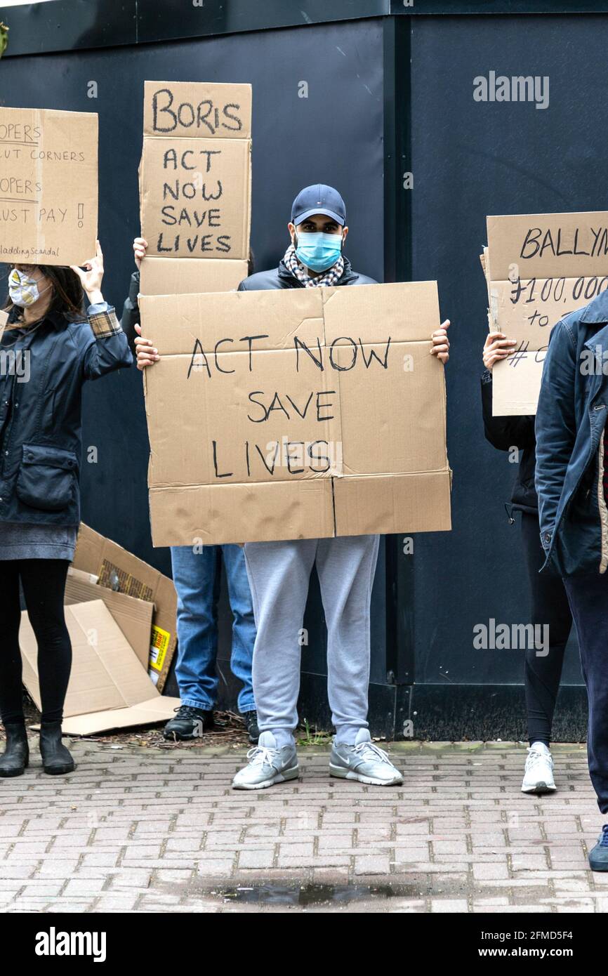 8 May 2021, London, UK - Protesters gathered in South Quay, Canary Wharf to protest against the unsafe and flammable cladding on buildings the day after nearby New Providence Wharf fire, man holding placard saying 'Act Now Save Lives' Stock Photo