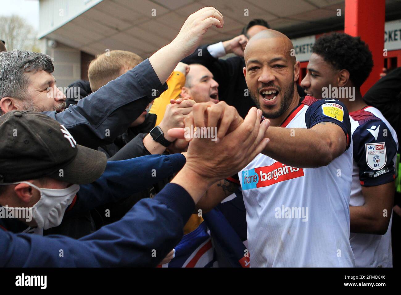 Alex Baptiste  of Bolton Wanderers celebrates with the Bolton fans after the match after his teams promotion to League One. EFL Skybet Football league two match, Crawley Town v Bolton Wanderers at the People's Pension Stadium in Crawley, West Sussex, England on Saturday 8th May 2021. this image may only be used for Editorial purposes. Editorial use only, license required for commercial use. No use in betting, games or a single club/league/player publications.pic by Steffan Bowen/Andrew Orchard sports photography/Alamy Live News Stock Photo