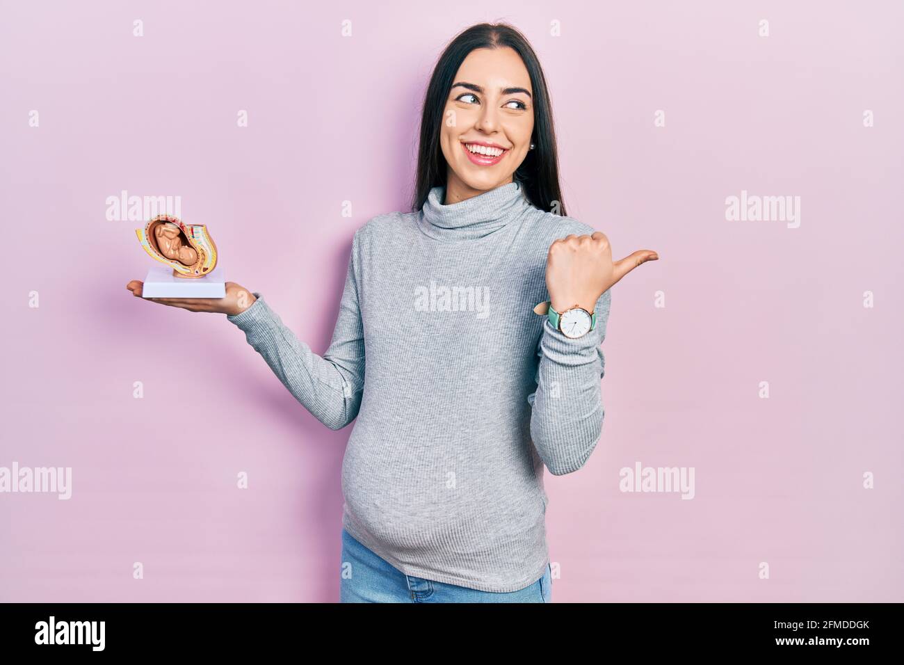 Beautiful woman with blue eyes expecting a baby, holding anatomic fetus ...