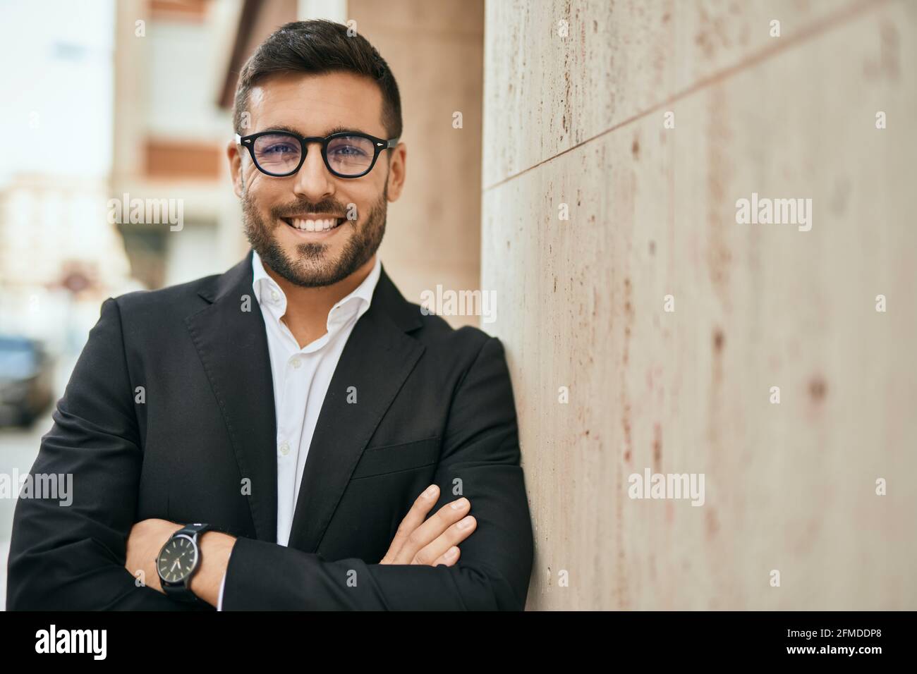 Young hispanic businessman with arms crossed smiling happy at the city ...