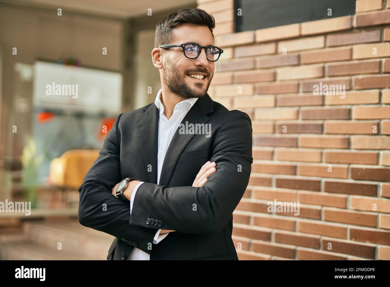 Young hispanic businessman with arms crossed smiling happy at the city ...