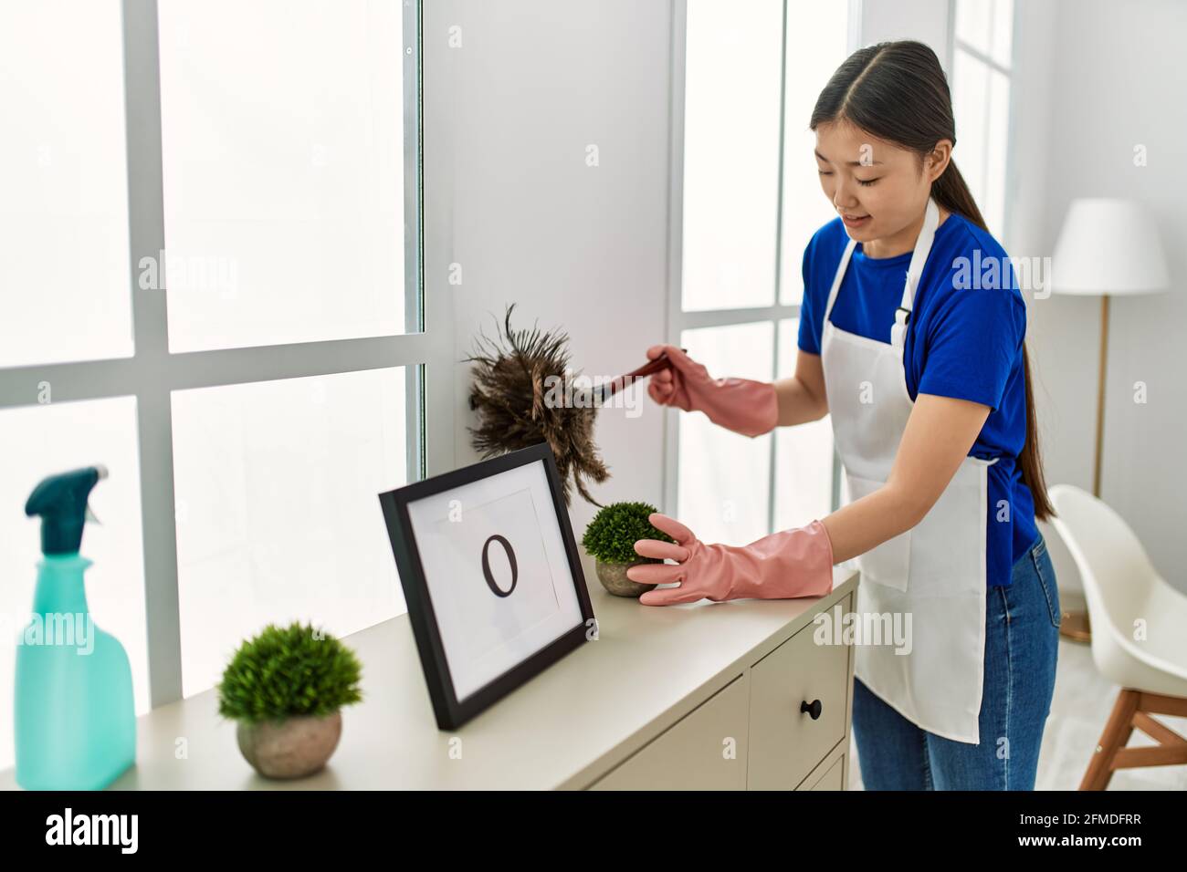 Young chinese housewife cleaning dust using duster at home Stock Photo ...