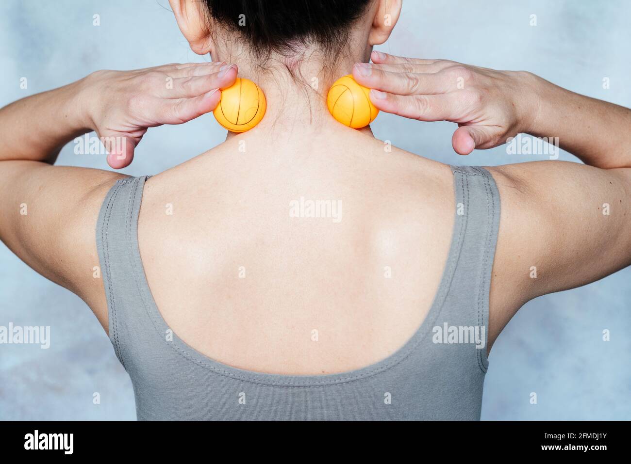 Young woman massages her neck with trigger point tennis ball used for