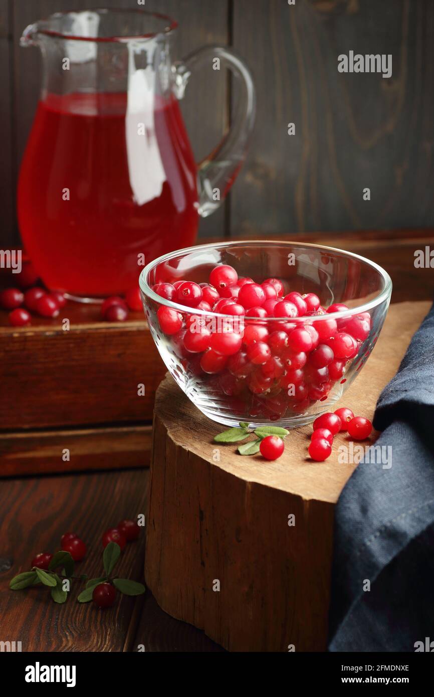 Cranberry cold drink in glass pitcher with red berries on wooden rustic background, closeup, winter christmas holiday drinks, healthy healing liquids, Stock Photo