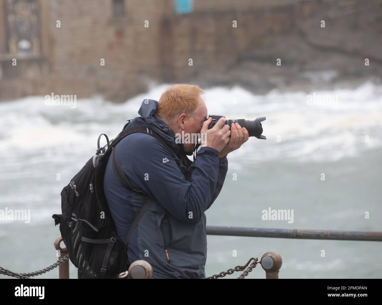 Porthleven,Cornwall,8th May 2021,A man takes photos of the rough sea and large waves  caused by the extremely strong winds in Porthleven, Cornwall. The Temperature was 12C, the forecast is for rain & strong winds over the next few days.Credit: Keith Larby/Alamy Live News Stock Photo