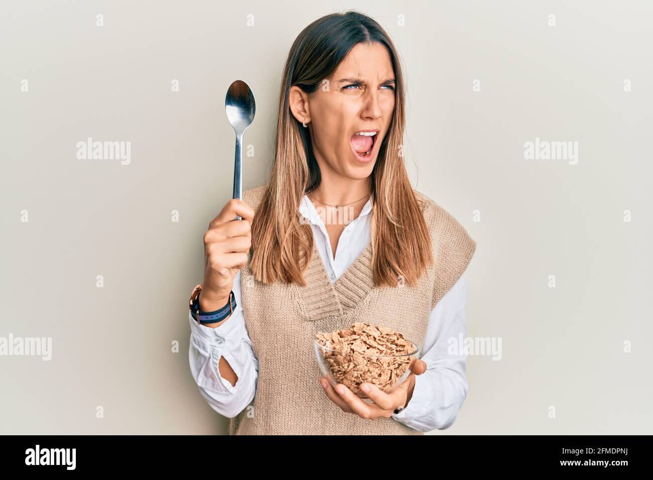 young woman eating healthy whole grain cereals with spoon