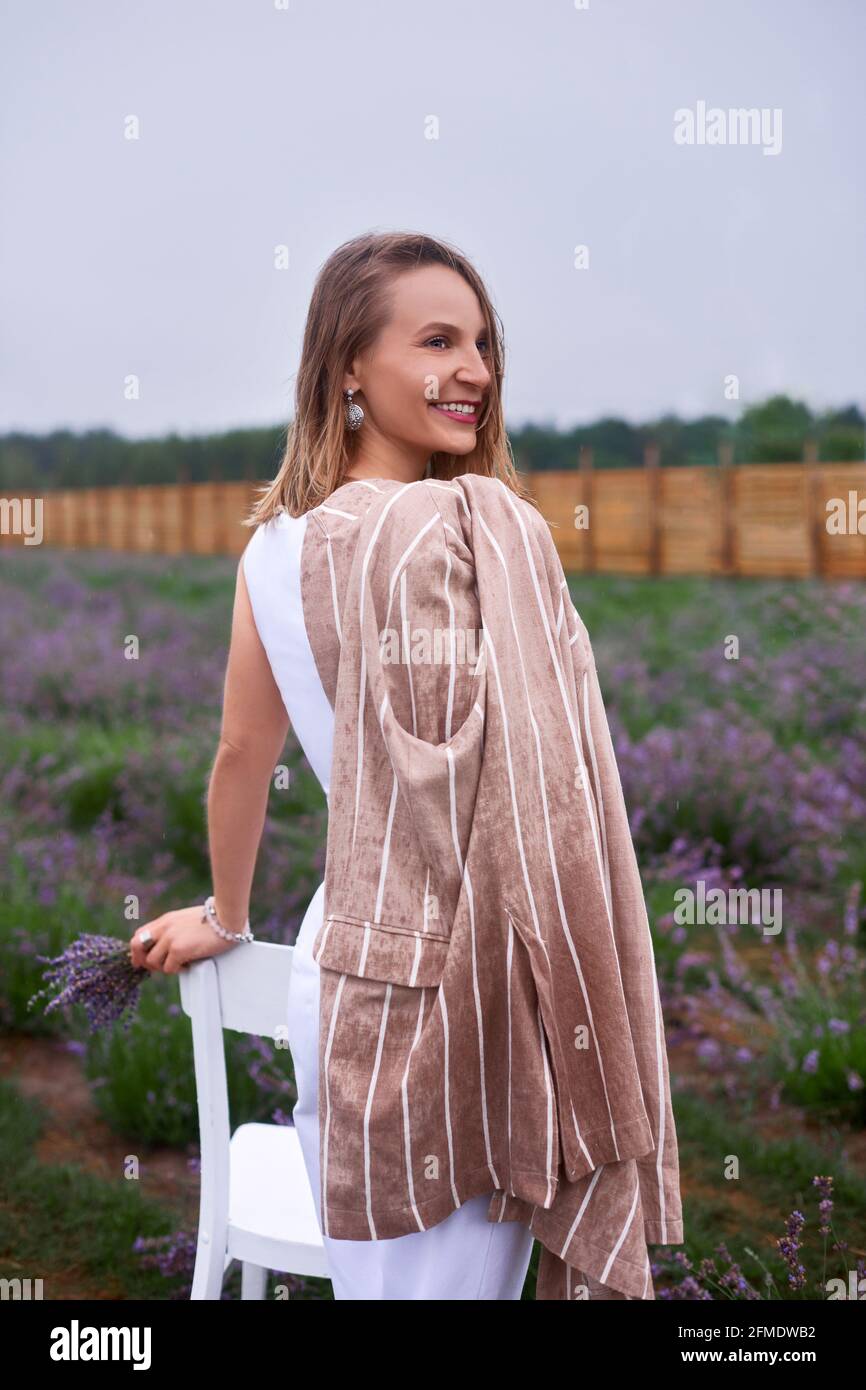 smiling woman in lavender take photo field with jacket soaked in rain. vertical shallow depth of field photo Stock Photo
