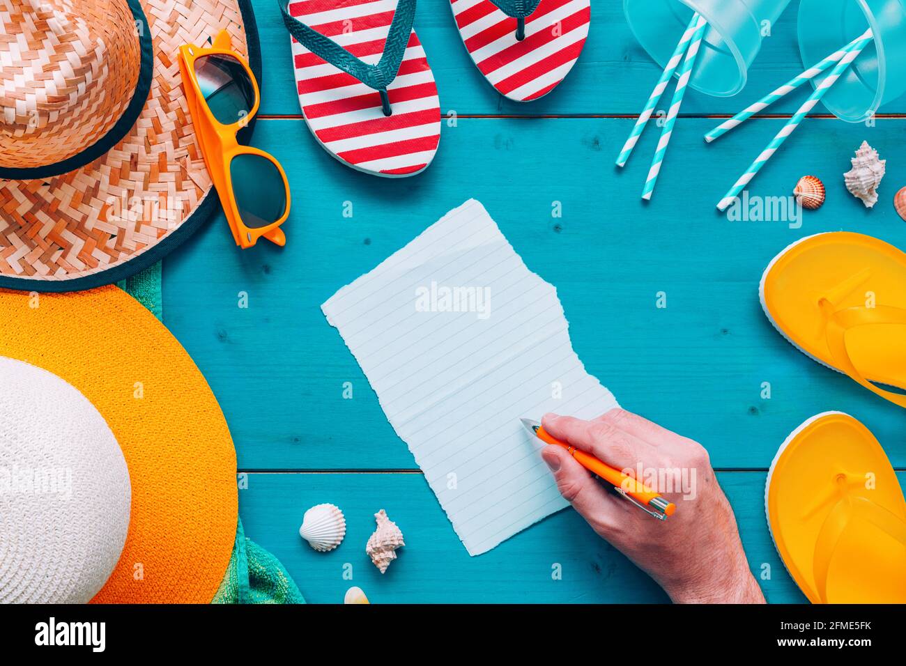 Man writing note on a piece of paper on the beach, top view flat lay ...