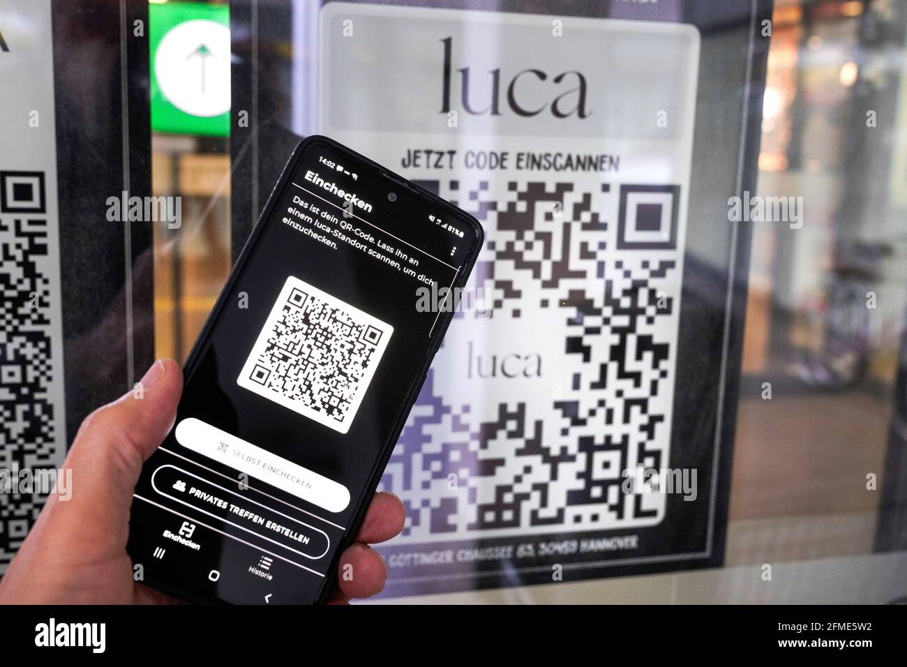 Luca app on a smartphone scans a Luca QR code at the entrance to a food market in Hanover. You can check in and out with your mobile phone and this enables corona infection chains to be traced. Hanover, Germany, 8 May 2021   ---   Luca-App auf einem Smartphone scannt einen Luca QR-Code am Eingang eines Lebensmittelmarktes in Hannover. Sokann man mit dem Handy ein- und auschecken und das ermöglicht die Rückverfolgung von Corona-Infektionsketten. Hannover, 8.5.2021 Stock Photo