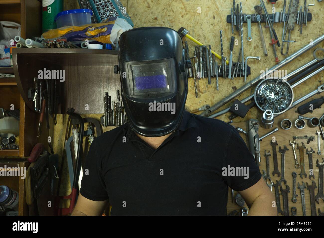Portrait of a young man in the workshop. The man is wearing a welder's mask. Stock Photo