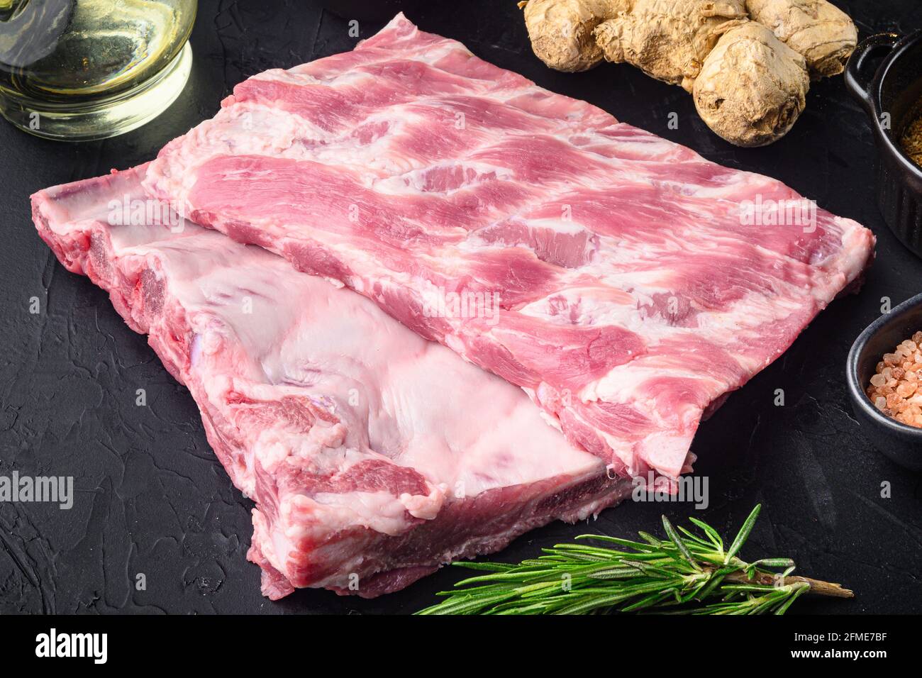 Fresh rack of raw pork spare ribs seasoned with spices set, on black ...