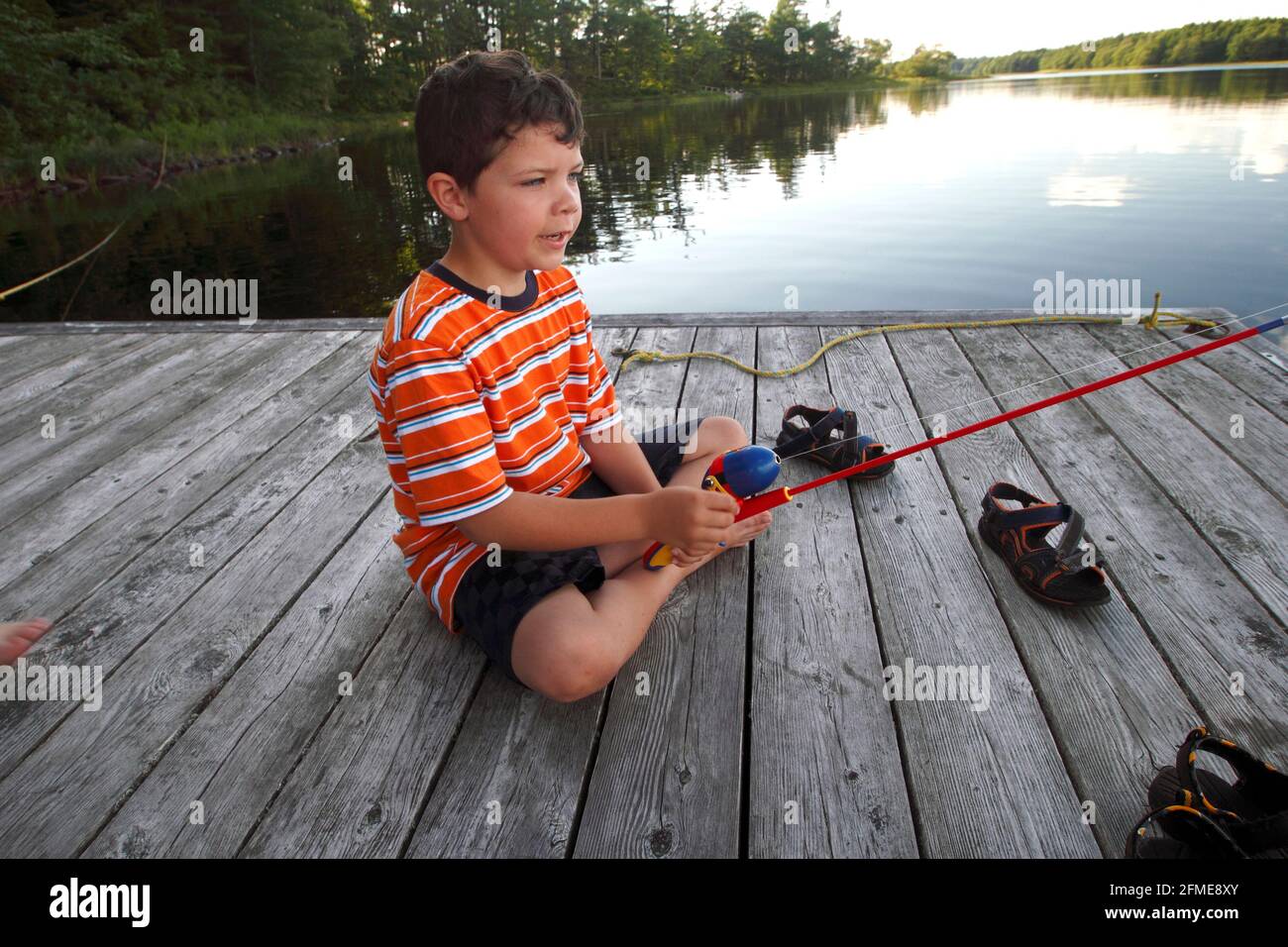 A 7 yr old boy fishing from a wharf Stock Photo
