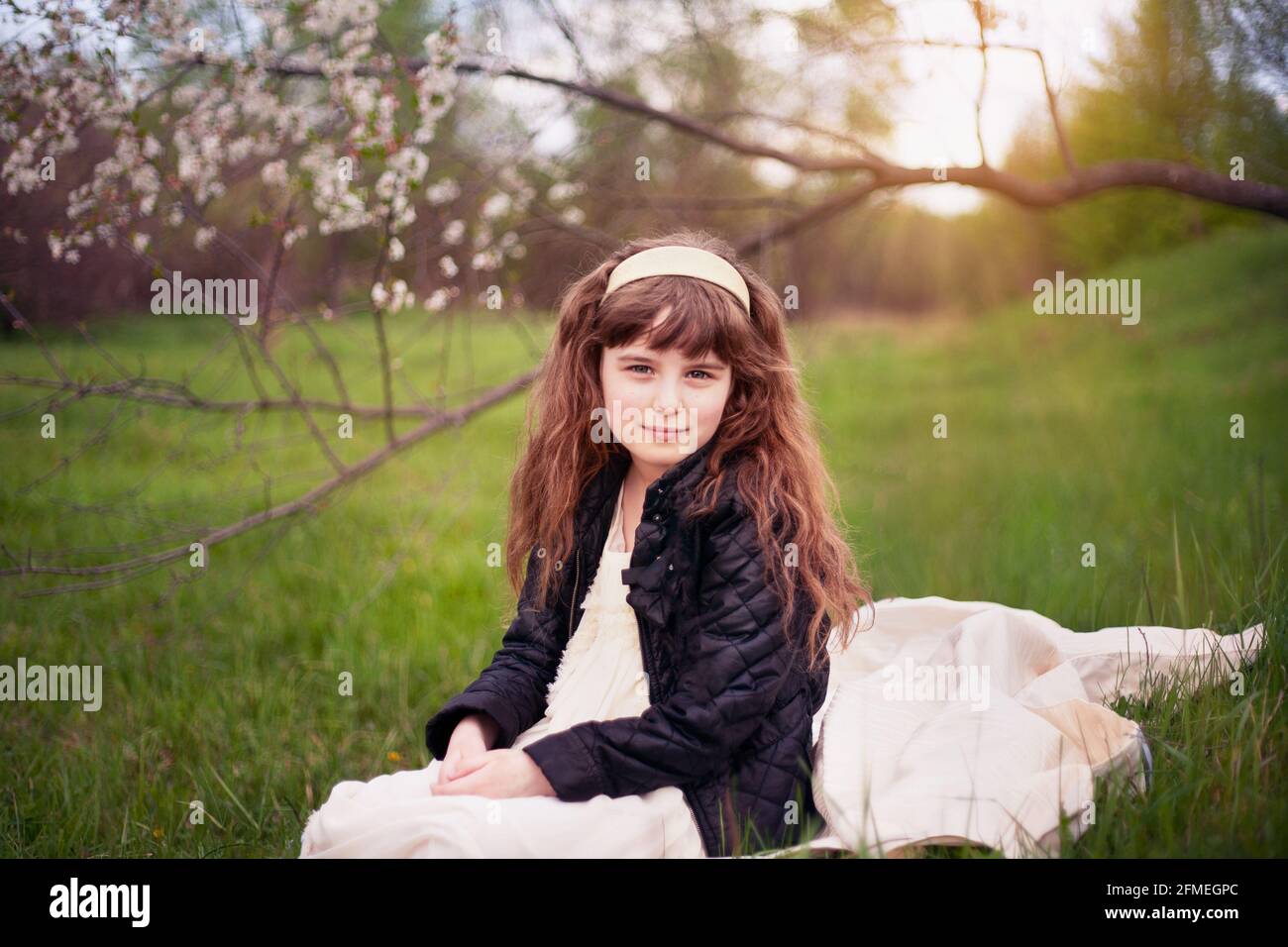 little girl in nature on a sunny summer day full of grass and flowers ...
