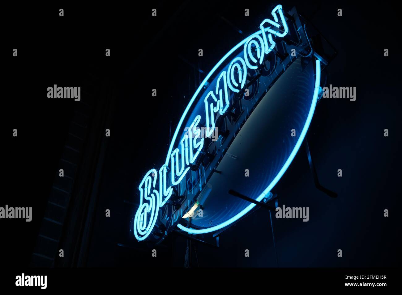 This is a photograph of a neon Blue Moon beer sign in a window of a bar in downtown Lafayette