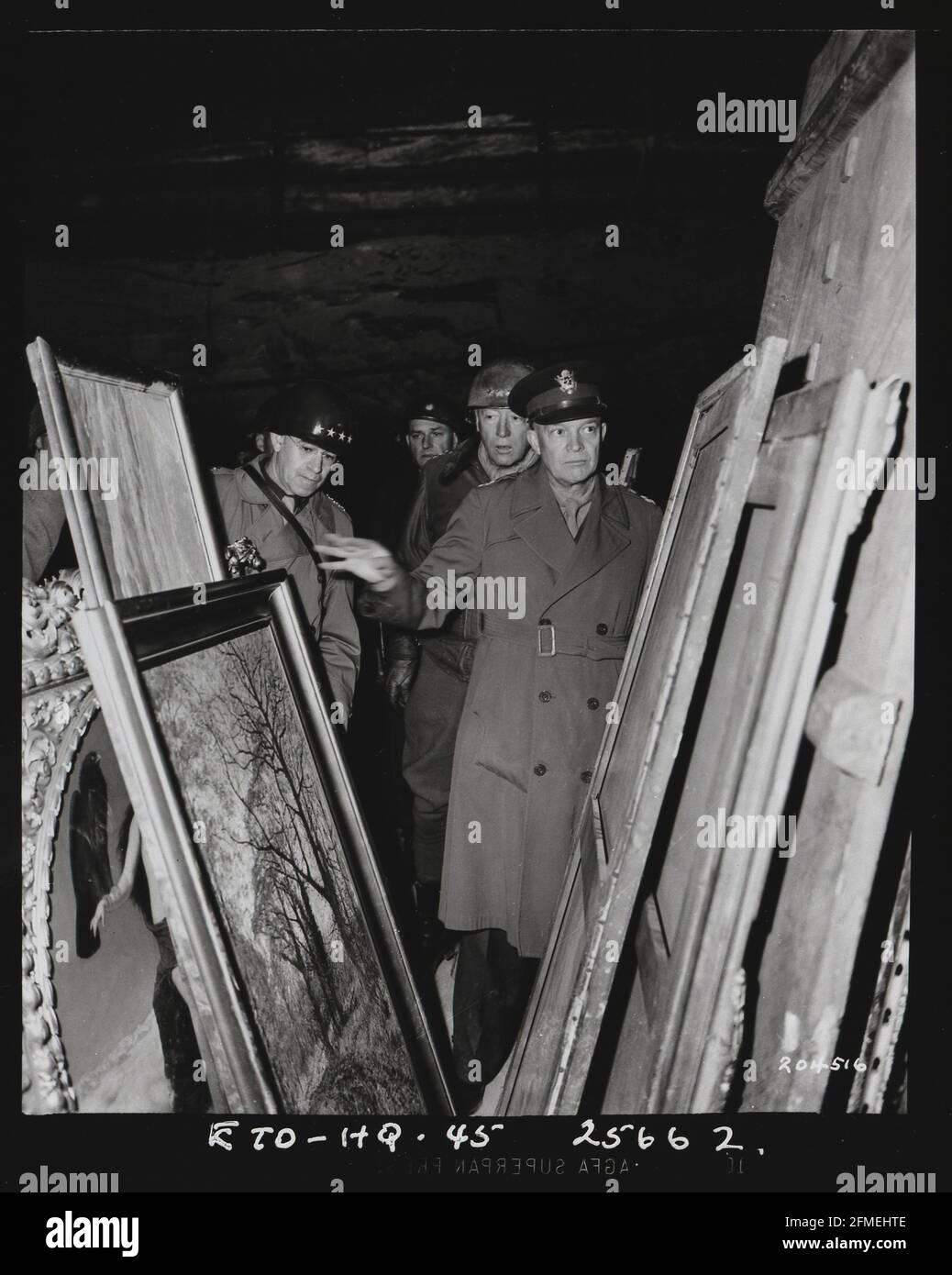 WWII World War Two Gen. Dwight D. Eisenhower inspects paintings in a salt mine at Merkers, near Gotha, Germany, where the Nazi government stored art treasures and gold, plundered in occupied countries, on April 12, 1945. The Supreme Allied Commander was accompanied by Gen. Omar N. Bradley, left, and Lt. Gen. George Patton Jr., immediately behind him. More than 20 percent of the art of Europe was looted by the Nazis under Hitler, and as many as 100,000 works are still thought to be missing. Stock Photo