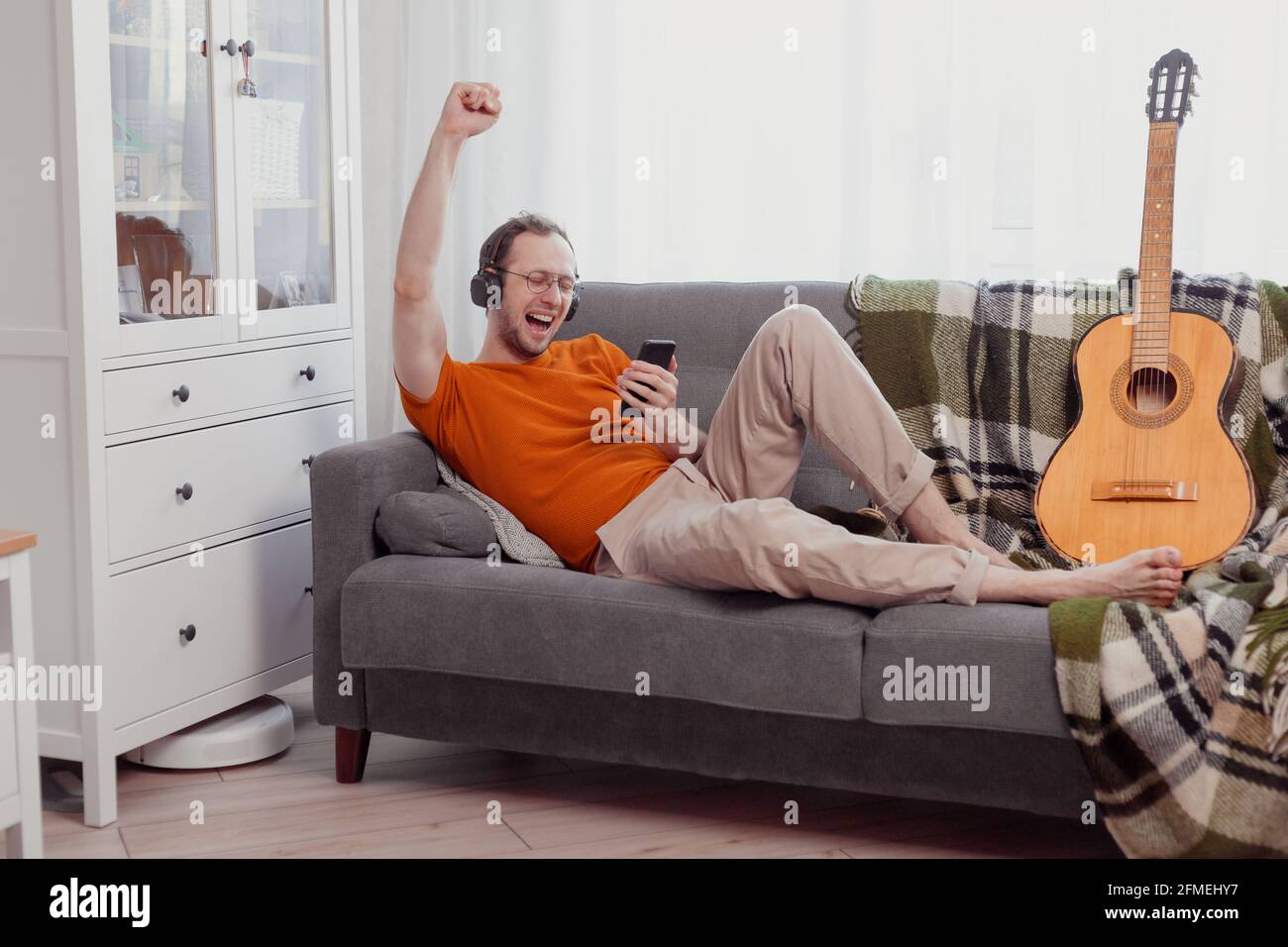 Handsome man playing on the guitar on the couch at home Stock Photo