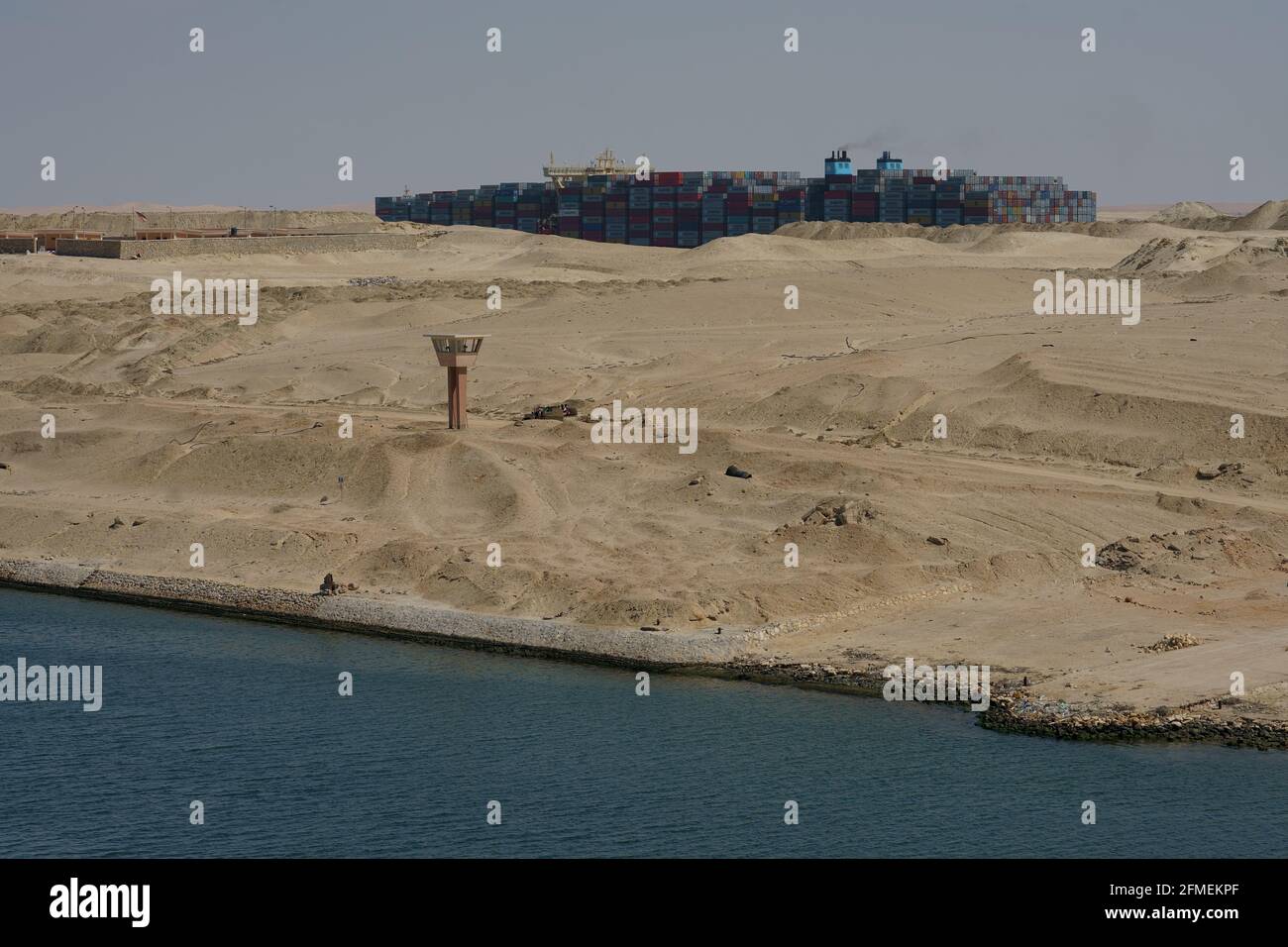 Container ship, proceeding between sand dunes on Sue Canal Stock Photo