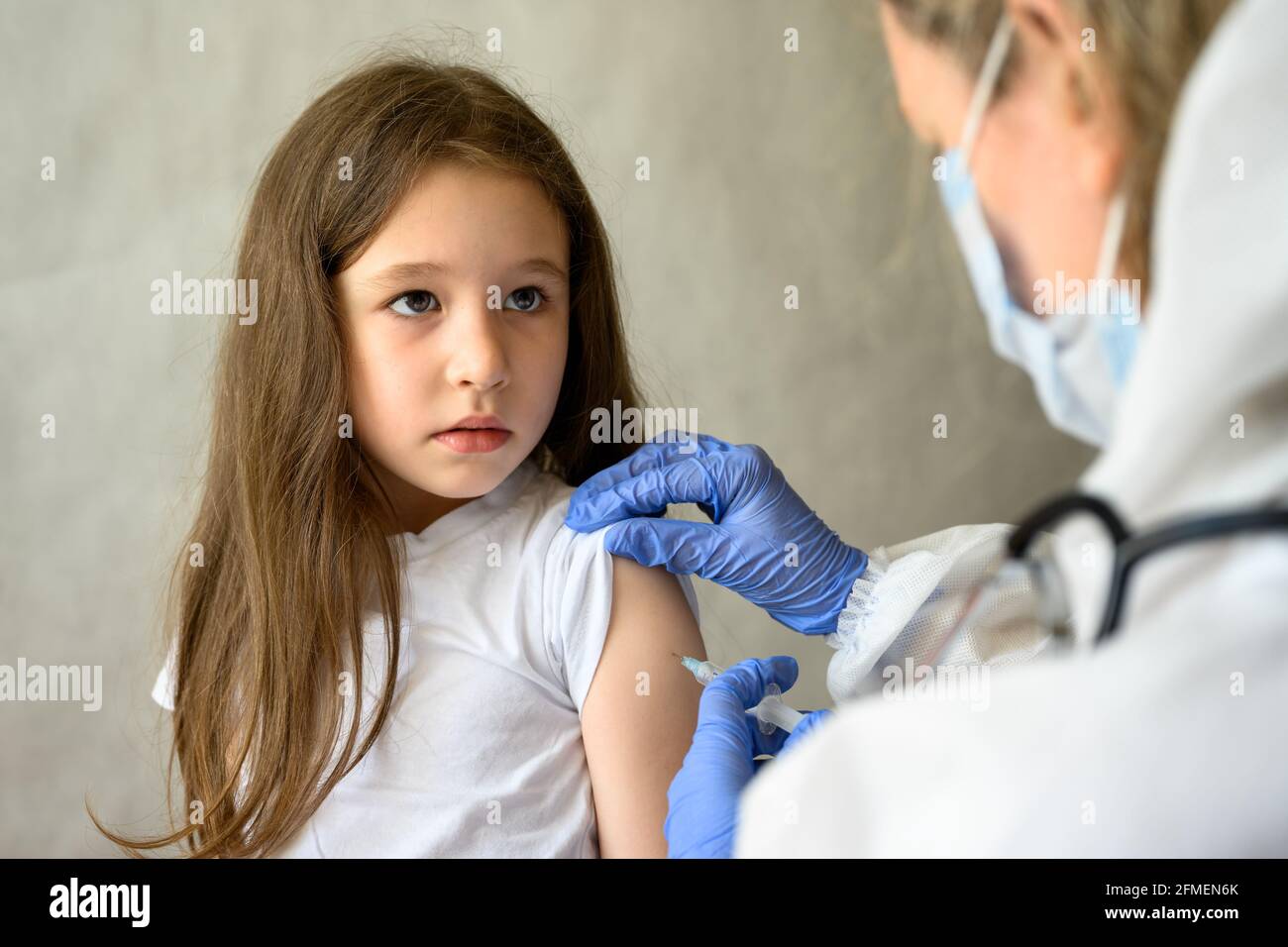 Vaccination of kid from COVID-19 or flu, cute little girl during coronavirus vaccine injection. Doctor makes shot to adorable child. Concept of immuni Stock Photo