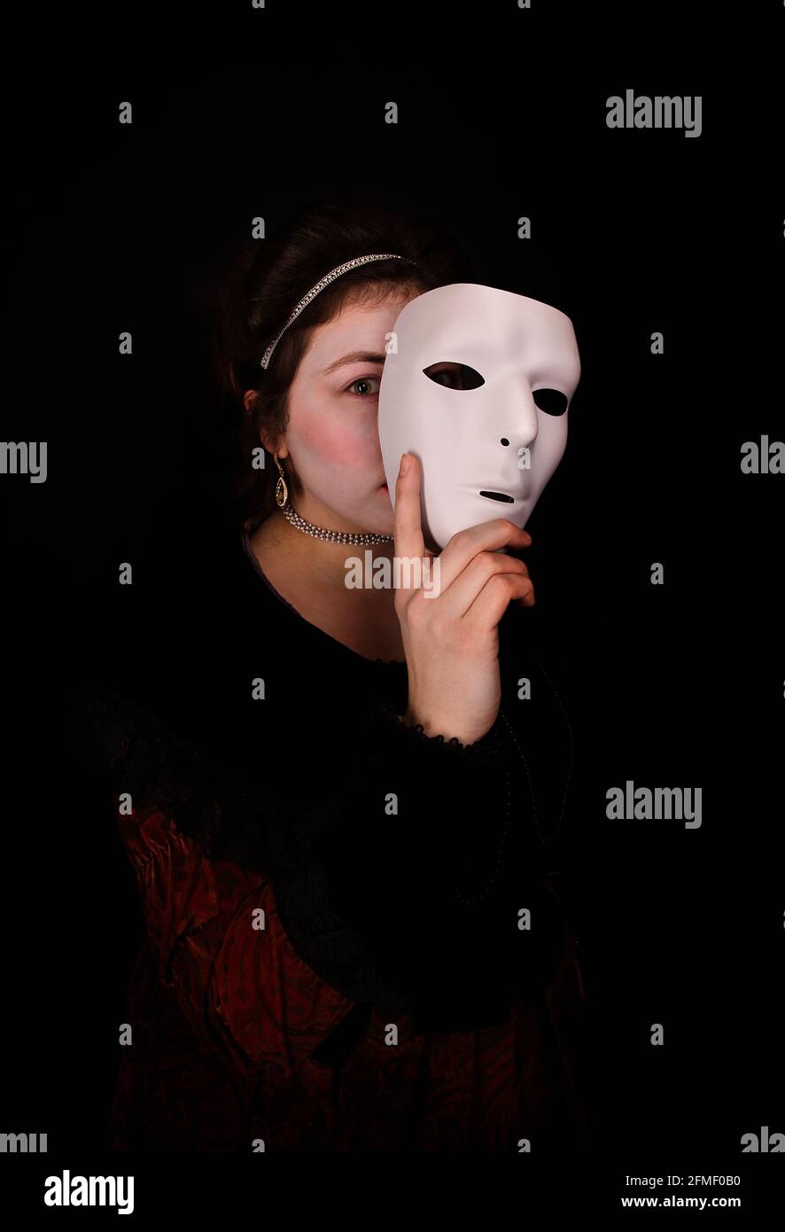 Woman in costume holding mask to her face Stock Photo Alamy