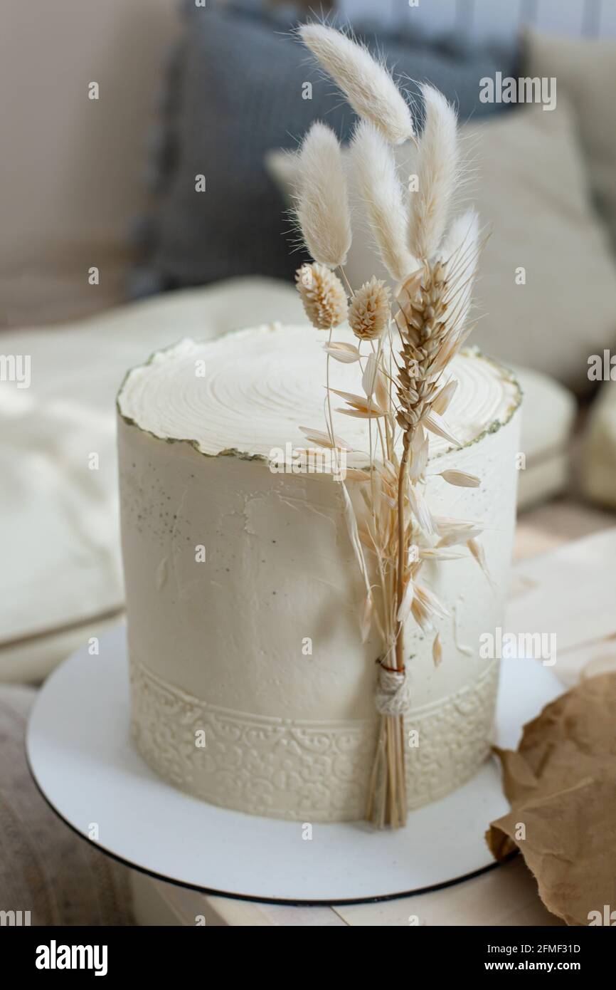 Amazing minimalistic cake cream beige decorated by dry ear of wheat cotton  in boho scandi style Stock Photo - Alamy