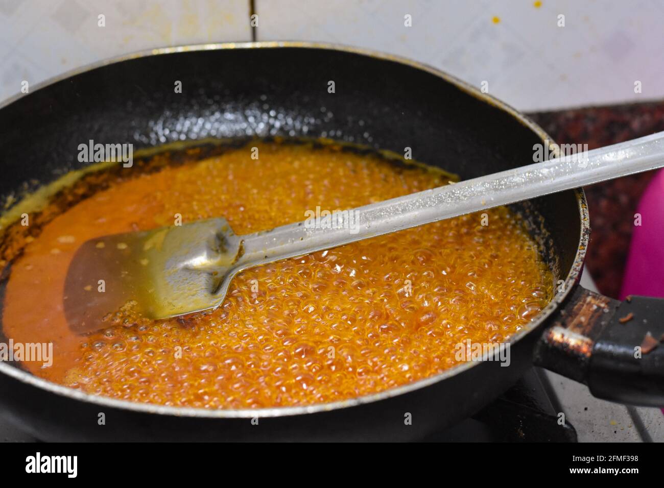 Simmering golden sugar syrup, steel spatula Stock Photo