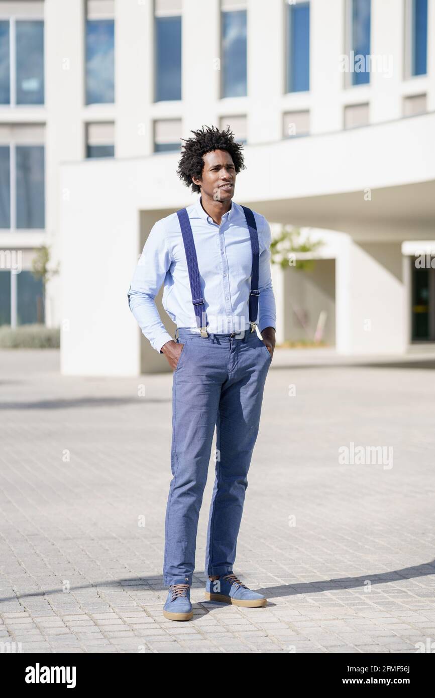 Black businessman wearing shirt and suspenders standing near an office ...