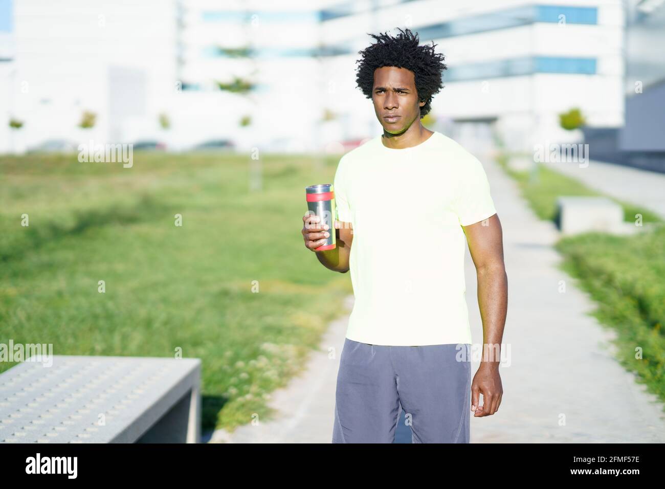 Black man drinking during exercise. Runner taking a hydration break. Stock Photo