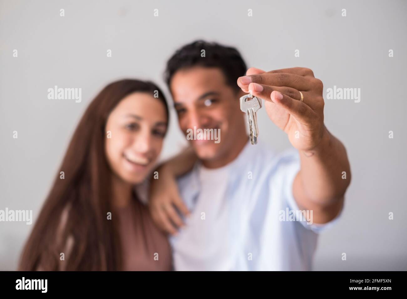 Close up of new home keys and young interracial couple smile and show ...