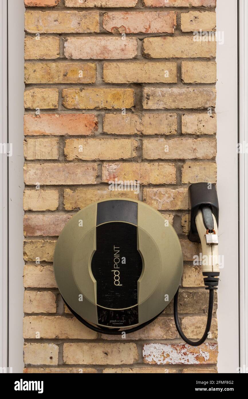 A  Pod Point electric car charger attached to an external brick wall, Cambridge, UK. Stock Photo