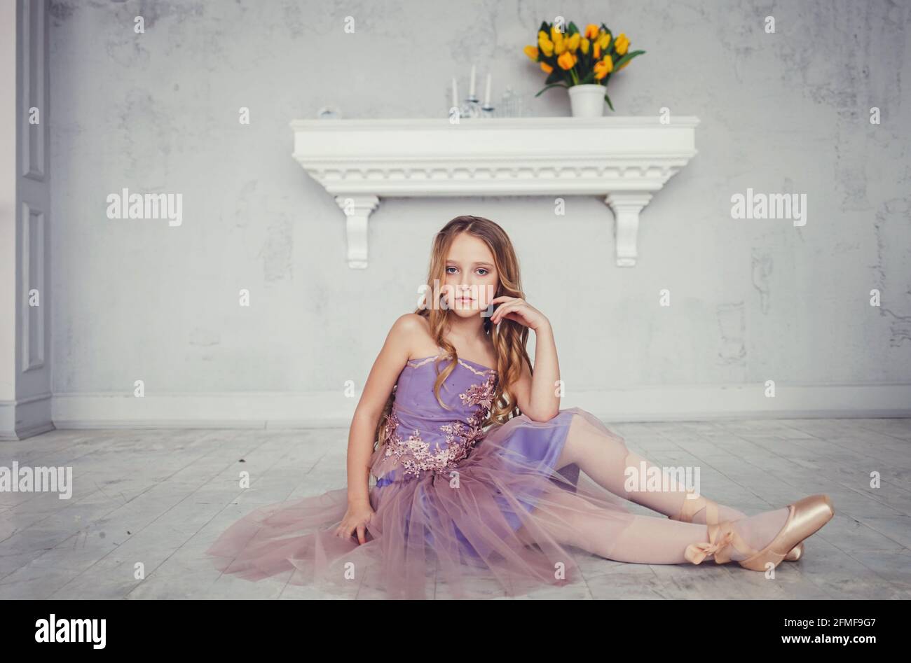 little girl in elegant dress posing while sitting in studio Stock Photo ...