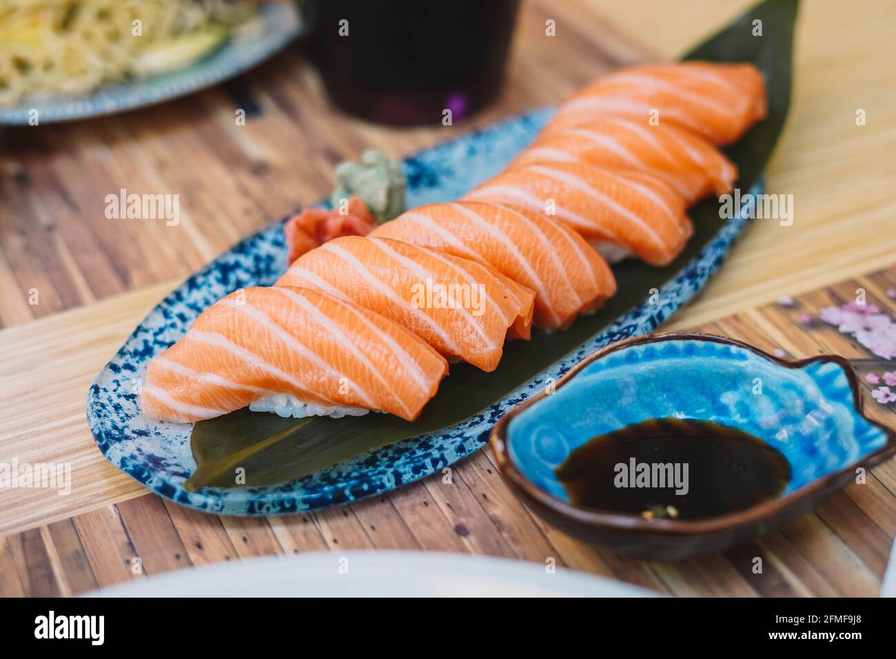 Sushi plate consisting of salmon nigiri, with soy sauce, served on a terrace. Stock Photo