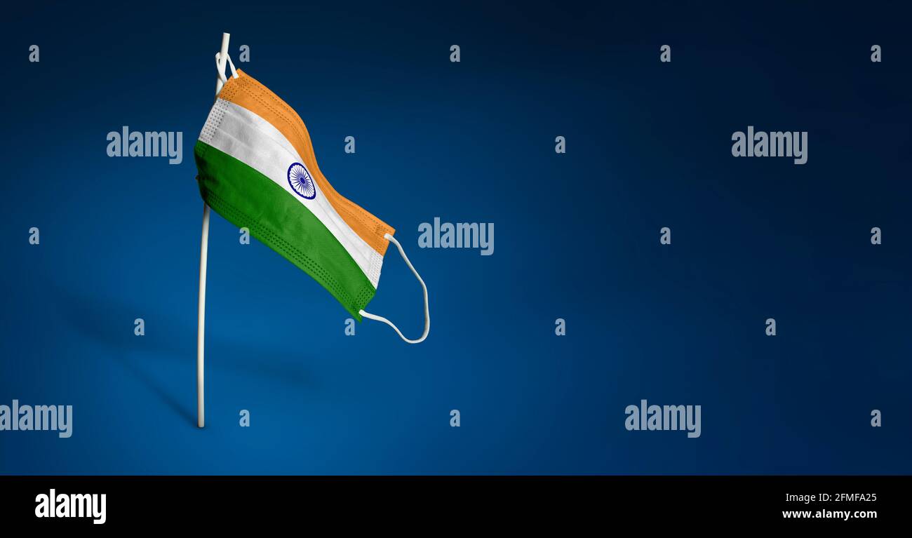 India mask on dark blue background. Waving flag of India painted on medical mask on pole. Virus Attack flag. Concept of The banner of the fight agains Stock Photo