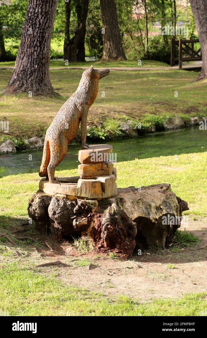 Crudely carved open air wooden sculpture of a standing wolf next the the Fuentona tributary of the Saja River Ruente Cantabria Spain Stock Photo