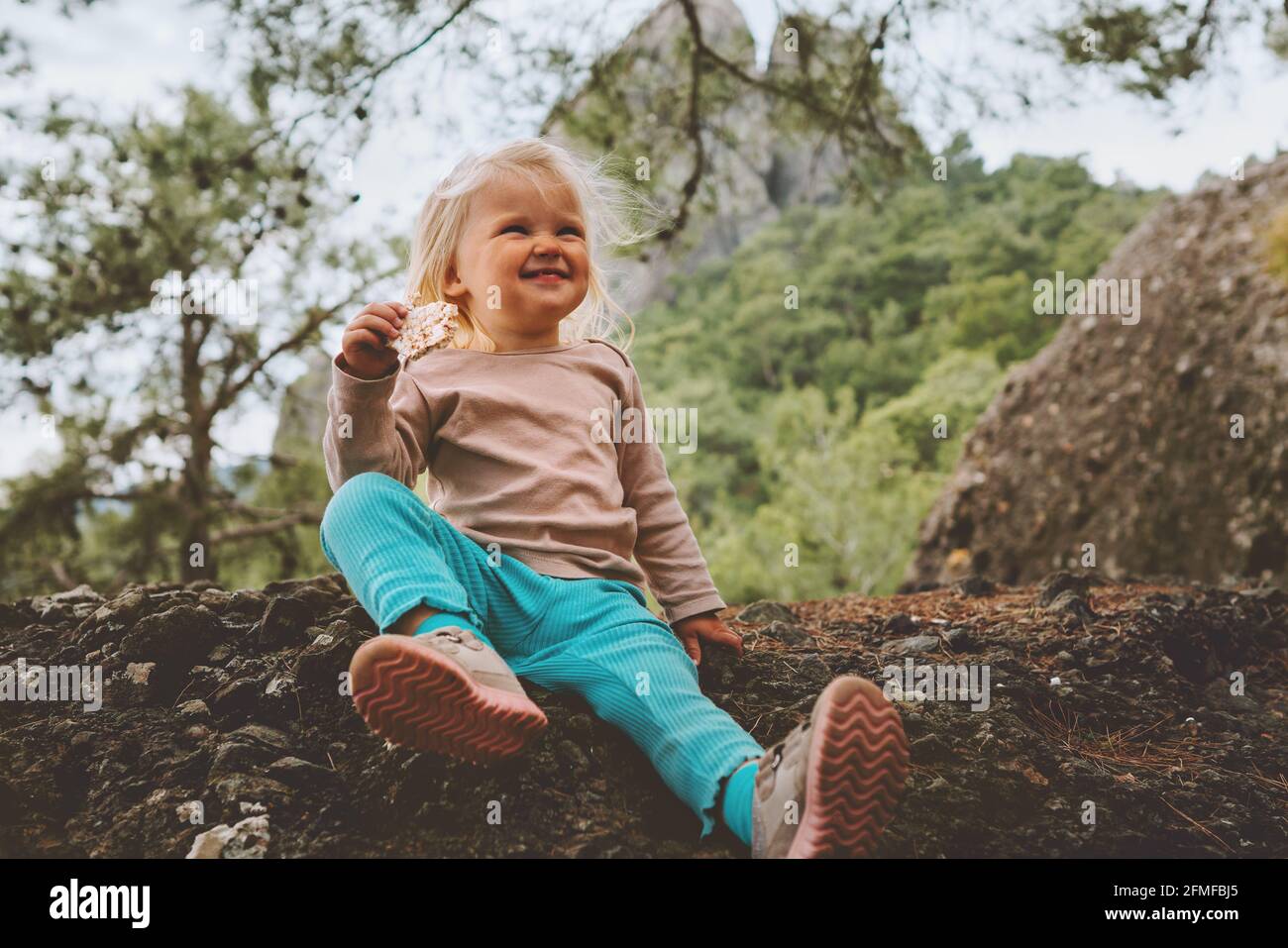 Child eating cookies outdoor in forest travel family vacation baby girl on picnic healthy lifestyle Stock Photo
