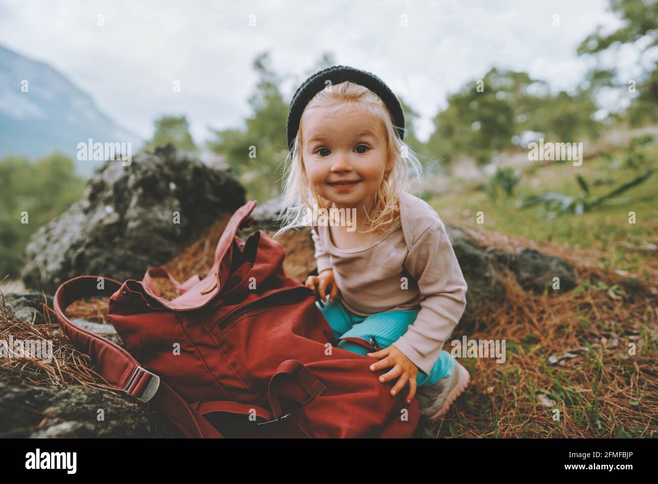 Child girl with backpack travel family vacations lifestyle 2 years old baby smiling hiking outdoor happy emotions Stock Photo