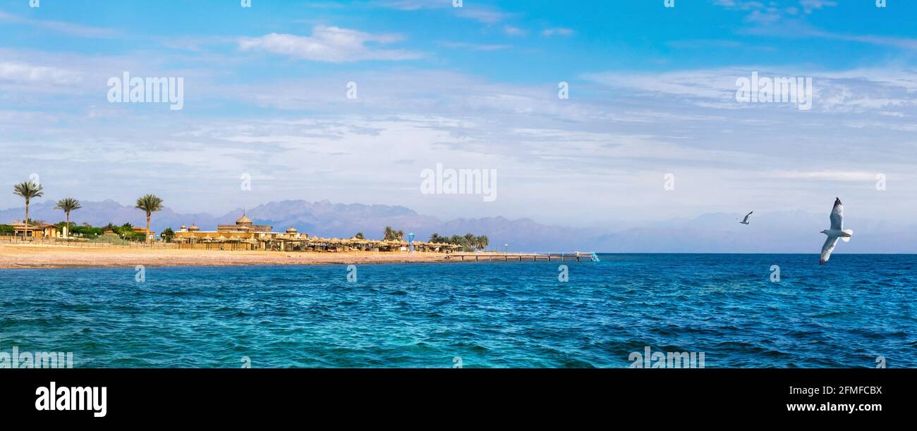 Landscape of the Red Sea coast near Dahab resort in Egypt with silhouettes of mountains of Jordan at skyline. Stock Photo
