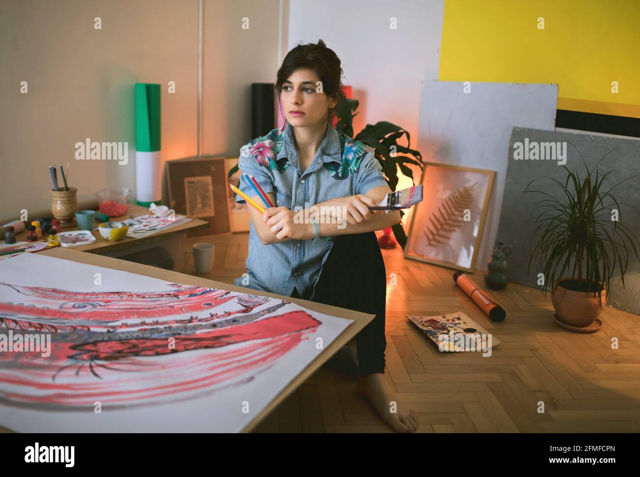 Portrait of female artist with paint brush and palette in studio ...