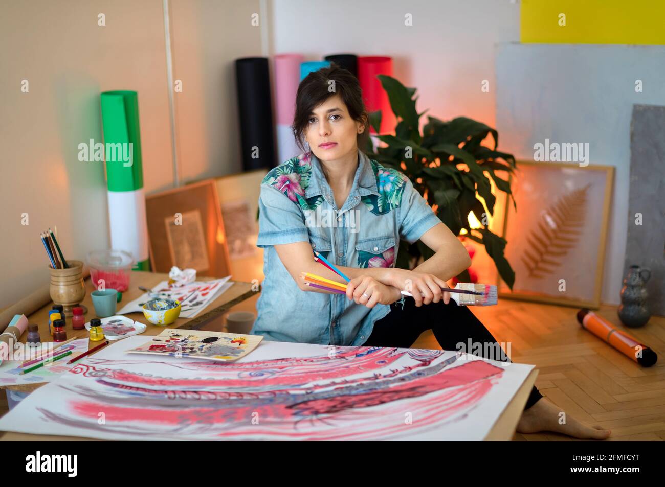 Portrait of female artist with paint brush and palette in studio ...