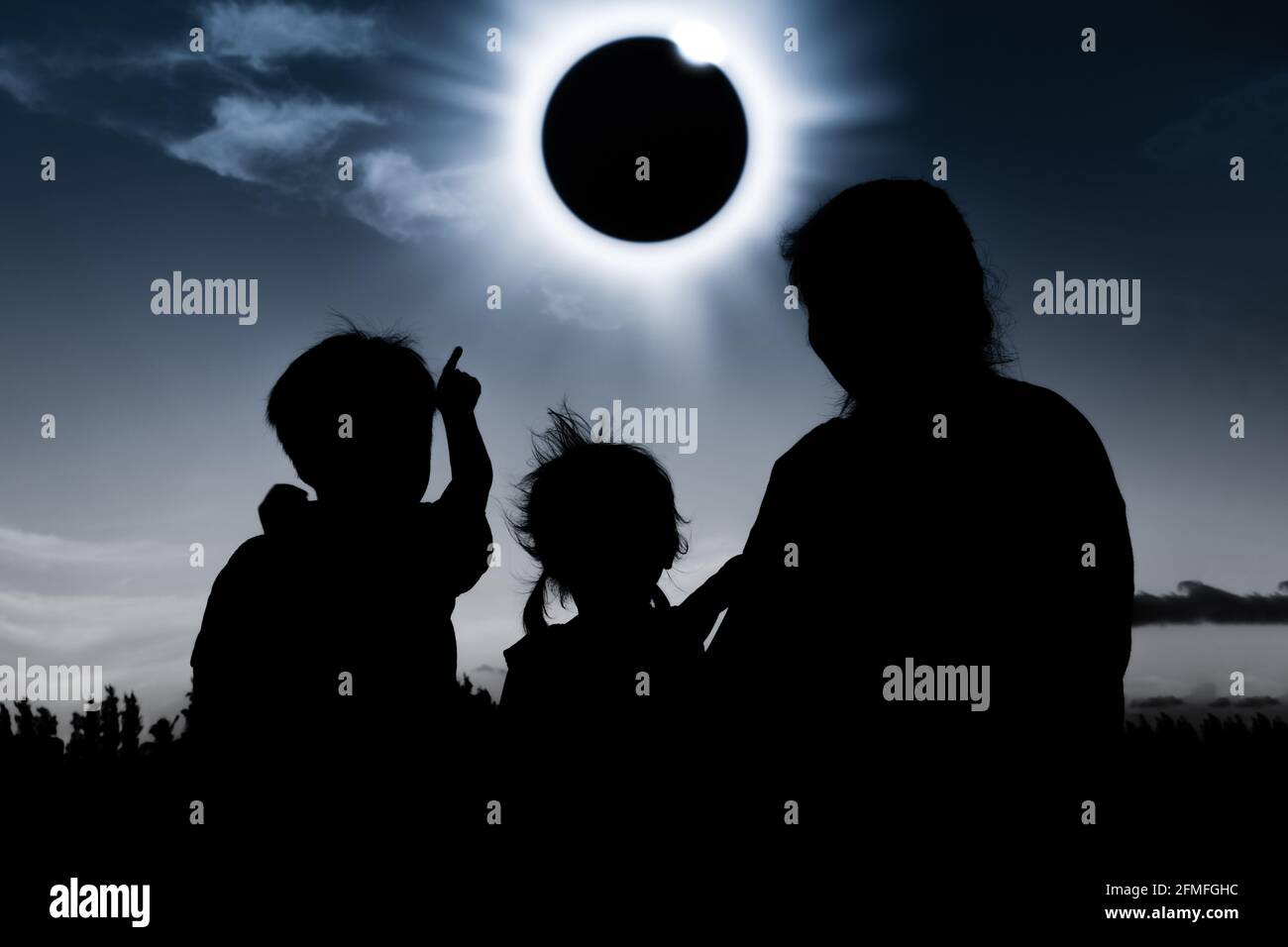 Natural phenomenon. Silhouette back view of mother and child sitting and relaxing together. Boy pointing to solar eclipse on dark sky background. Happ Stock Photo