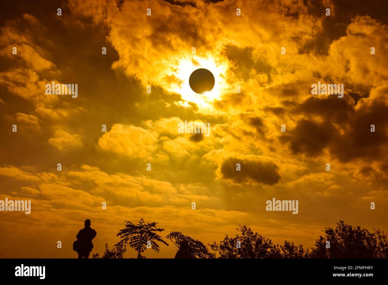 Amazing scientific natural phenomenon. The Moon covering the Sun. Silhouette of man admire the total solar eclipse with diamond ring glowing on golden Stock Photo