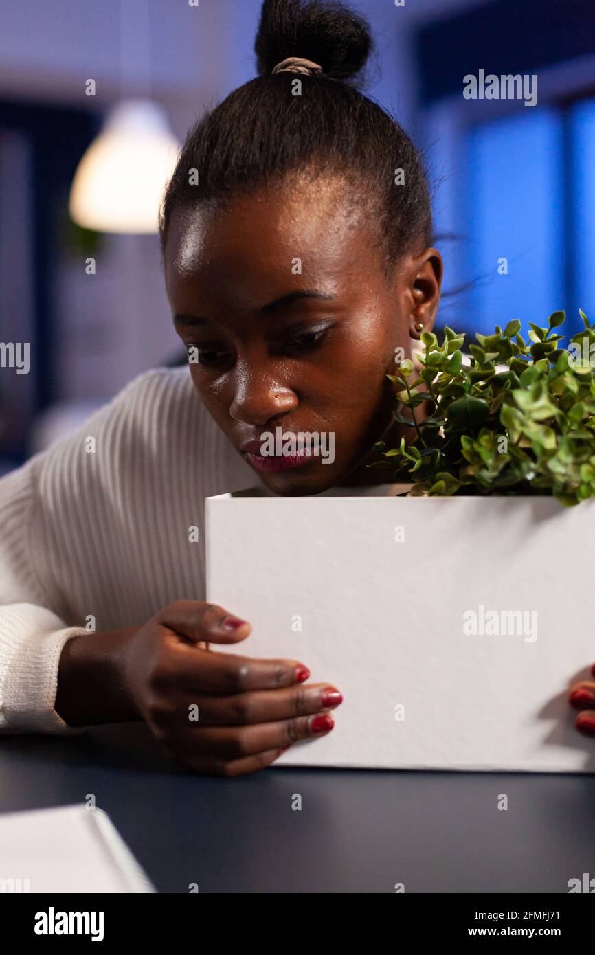 Close upf sad depressed african woman after bing dismissed from work during economy crisis. Unemployed packing things late at night. woman leaving workplace office in midnight. Stock Photo