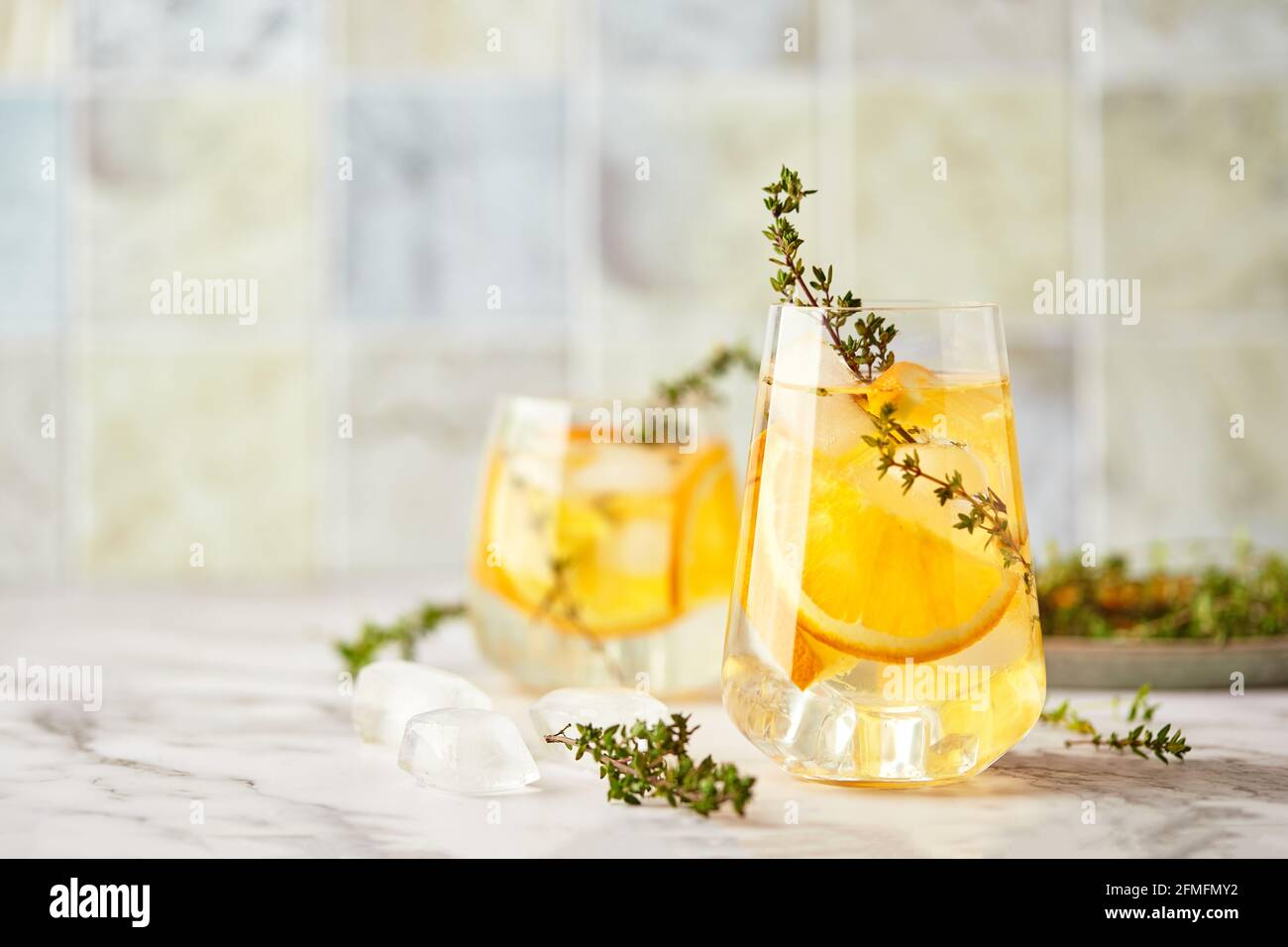 Refreshing cocktail with ice, orange and thyme. Refreshing summer homemade alcoholic or non-alcoholic cocktail or mocktail, or Detox infused flavored Stock Photo