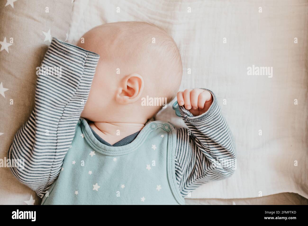 close-up of sleeping baby boy covering his eyes with his arm Stock Photo