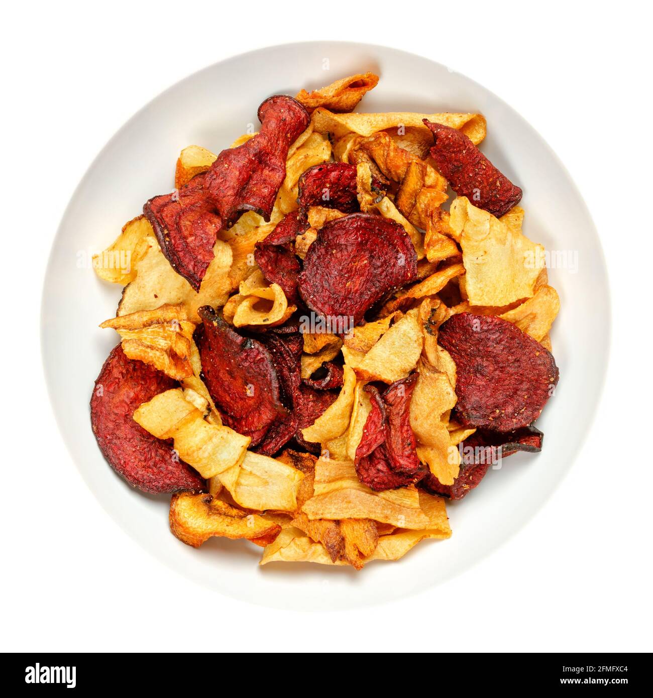 Mixed root vegetable crisps, in a white bowl. Mix of sliced root vegetables, parsnips, beetroots and carrots, fried in sunflower oil, with sea salt. Stock Photo