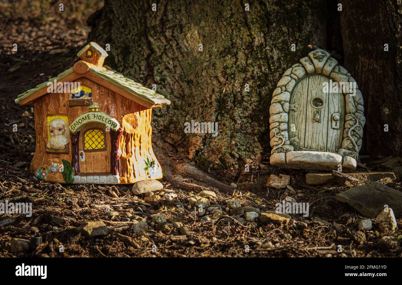 Gnome Hollow house resin yard decoration and gnome door at base of tree in Lancaster County, Pennsylvania, during spring Stock Photo