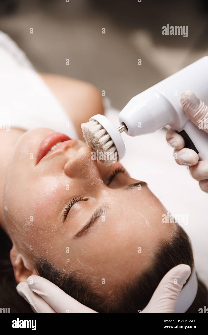 Face of woman at beauty salon, beautician making brossage therapy, brushing procedure on female client face, cosmetologist using deep cleansing Stock Photo
