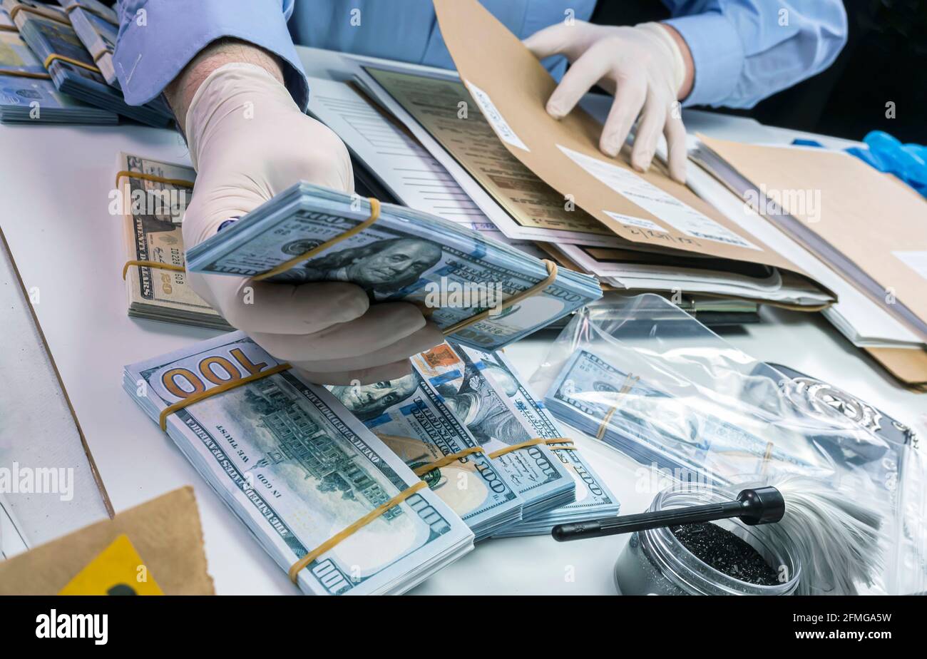 Specialised police officer notes dollar banknote reference of a robbery, conceptual image Stock Photo