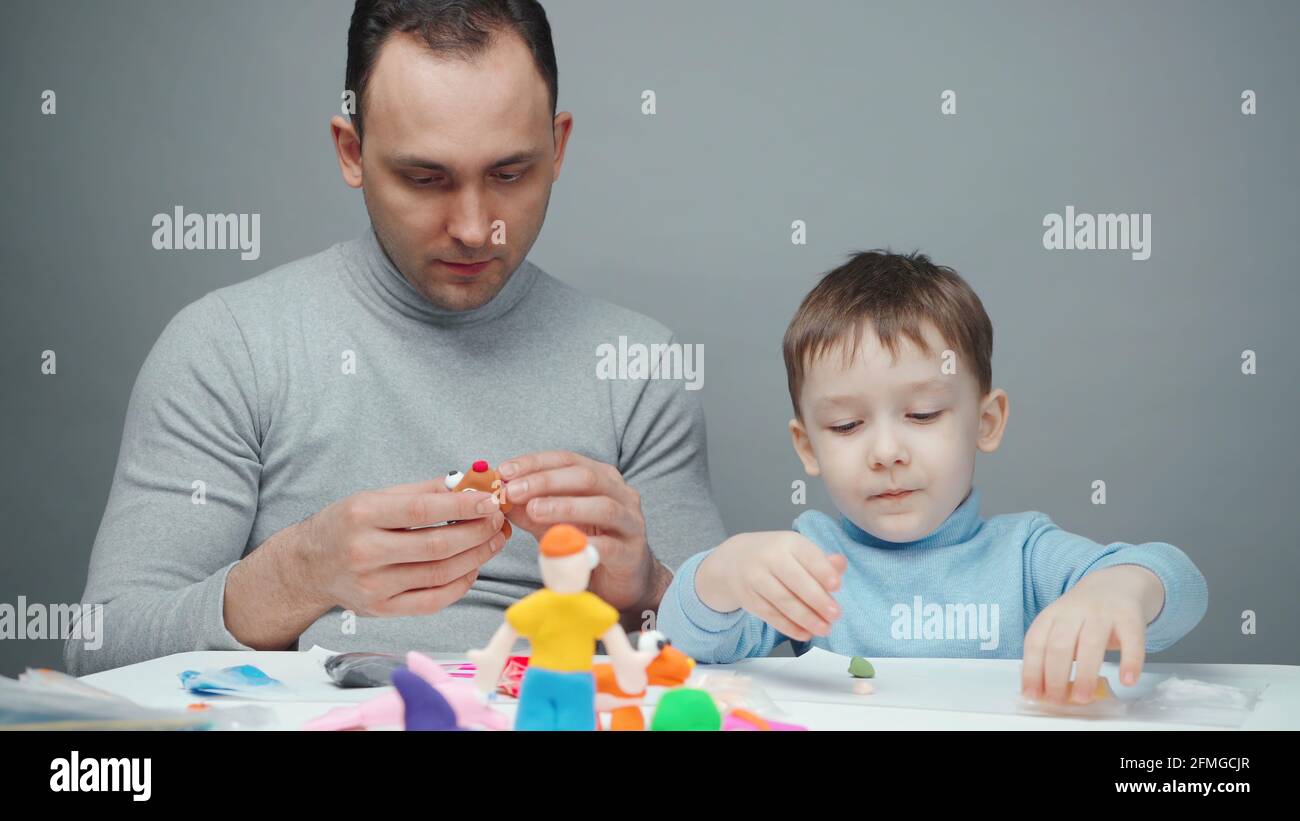 Shooting of dad and little boy making animals from plasticine Stock Photo