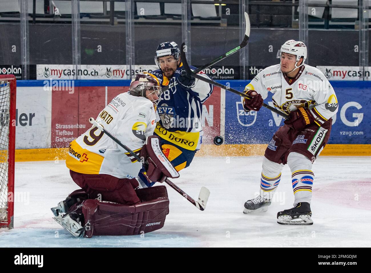 # 5 Enzo Guebey (Geneva) and # 79 goalkeeper Daniel Manzato (Geneva) stop Yannick-Lennart Albrecht # 28 (EV Zug) during the National League Playoff Final ice hockey game 3 between EV Zug and Geneve-Servette HC on 07.05.2021 in the Bossard Arena in Zug. (Switzerland/Croatia OUT) Stock Photo